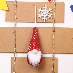 Close-up of a festive red knitted Christmas gnome ornament with white beard and ribbon
