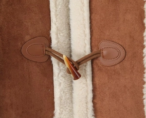 Detailed macro view of brown faux suede fabric with soft white shearling lining and horn button