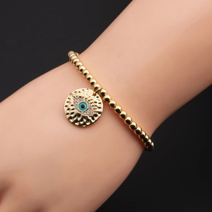Detailed macro view of gold plated evil eye bracelet with blue zircon inlay on wrist