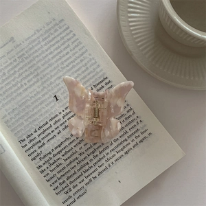 Macro shot of butterfly hair claw with marble texture on an open book background