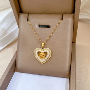 Close-up of golden heart pendant with embossed rose and sparkling zircon inlay