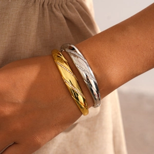 Close-up of 18k gold and silver plated bangles with spiral texture and zircon inlay