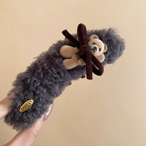 Detail of grey plush claw clip featuring a small teddy bear and dark brown bow detail