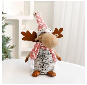 Detail of Christmas reindeer plush doll in grey knit hat on a white table setting