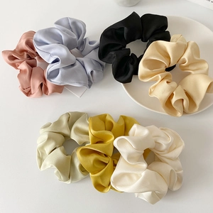 Set of 7 colorful satin scrunchies in pastel tones on a white plate background