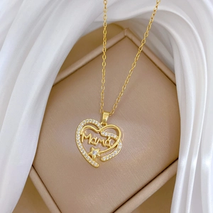 Macro d'un collier cœur doré serti de zircons avec gravure Mama sur de la soie