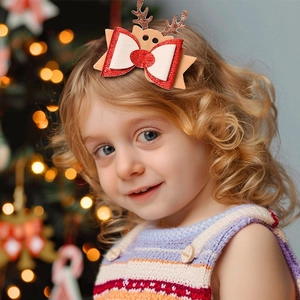 Close-up of a child wearing a Christmas bow hair clip with reindeer antlers and red glitter