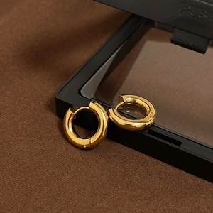 Close-up of polished 18k gold chunky hoop earrings on a textured display box