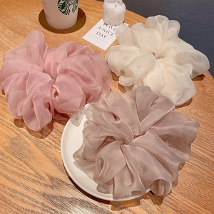 Detailed view of three oversized organza scrunchies in pink, white, and taupe colors