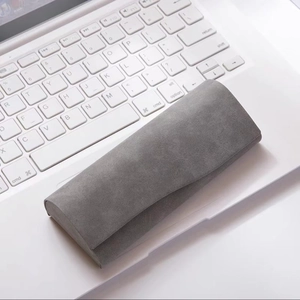 Gray suede textured glasses case resting on a white laptop keyboard in a modern setting