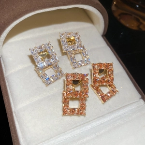 Macro detail of 18K gold-plated square hollow earrings with zircon inlay in a jewelry box