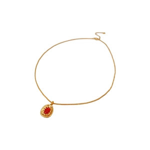 Vintage gold necklace with oval red gemstone pendant on a minimalist white background