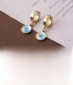 Close-up of gold stainless steel hoop earrings with evil eye pendants and zircon