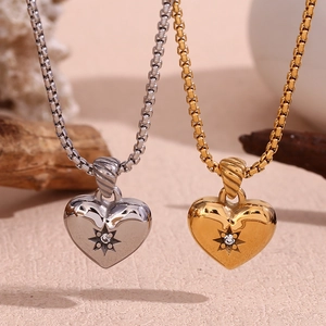 Macro detail of gold and silver heart pendants with starburst zircons on box chains