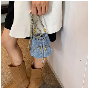 Blue denim camellia bucket bag with gold chain strap shown on model for size reference
