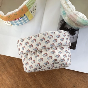 Quilted fabric cosmetic storage baskets with floral patterns on a wooden tabletop
