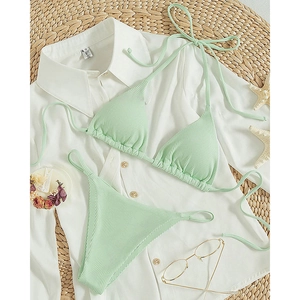 Flat lay of mint green ribbed halter bikini set with starfish and summer vacation decor