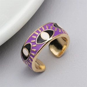 Close-up of golden adjustable evil eye ring with purple enamel and sunburst details