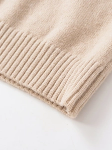 Close-up of beige knit sweater showing ribbed cuff texture and soft wool material