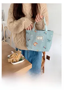 Gros plan du sac en toile cyan avec broderie papillon 3D et étiquette de logo