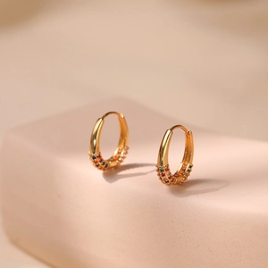 Detailed macro view of 18K gold-plated oval hoop earrings with multicolored zircons