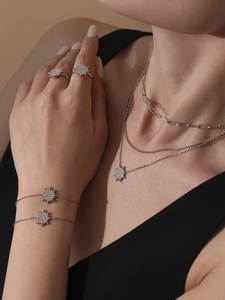 Detailed view of silver sunburst pendant necklace and ring set with sparkling zircons