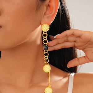 Close-up of vintage golden drop earrings with black gemstone and embossed metal details