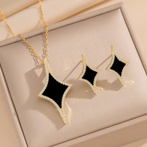 Golden jewelry set with black geometric pendants and rhinestones in a luxury box