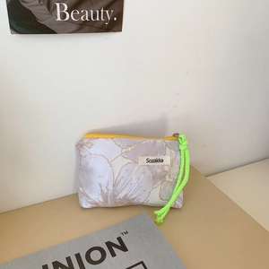 Detailed macro view of white floral jacquard makeup bag with neon green cord zipper pull