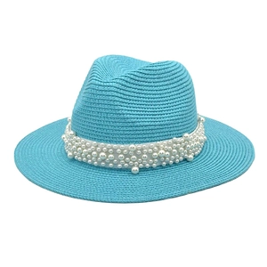 Detail of sky blue straw fedora hat featuring white ribbon and elegant pearl embellishments