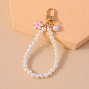 Close-up of pearl bead keyring with pink flower pendant and golden metal clasp