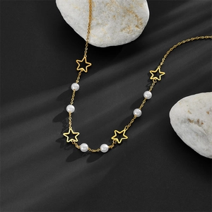 Élégant collier doré avec des breloques étoiles évidées et des perles sur fond gris