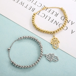 Detailed shot of Hamsa hand and heart bead bracelets in gold and silver stainless steel