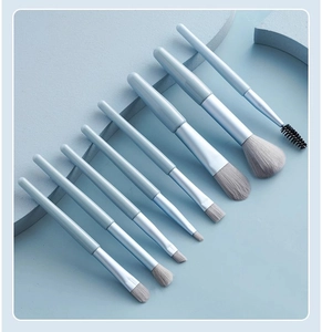 Close-up of 8-piece light blue makeup brush set with grey bristles on matching background