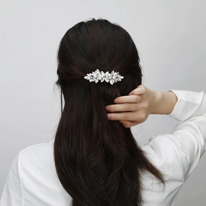 Detail view of rhinestone floral hair clip with white pearls on a model back hairstyle