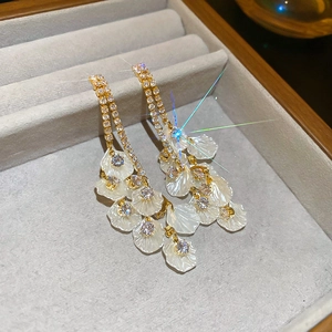 Détail de boucles d'oreilles en or 18k avec pompons en zircon et pétales de fleurs