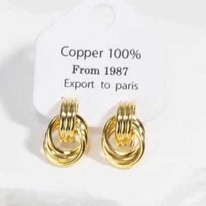 Detailed close-up of interlocking gold copper hoop earrings on a white jewelry display card