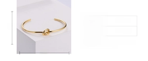 Detail showing gold knotted cuff bracelet with size measurements and 57mm inner diameter