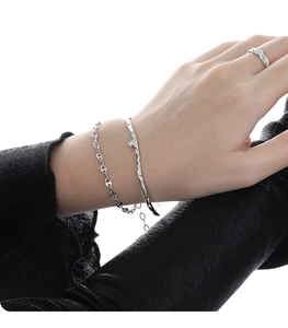 Detail showing irregular wavy silver bangle and anchor link bracelet on a woman's wrist