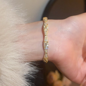 Close-up of gold-plated bangle featuring quilted texture and sparkling zircon inlay