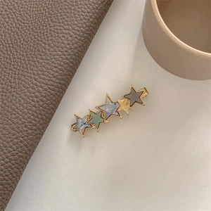 Detail of star-shaped hair clip with marble texture in gold-tone metal base