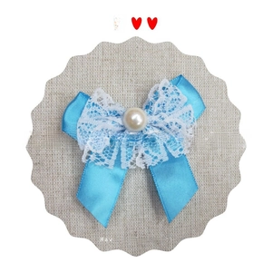 Detail of blue satin and white lace mermaid bow with a central pearl bead embellishment