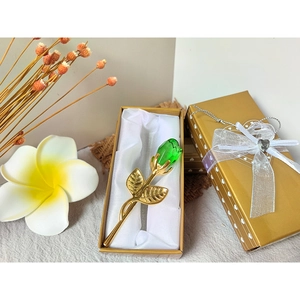 Detailed view of green crystal rose in a gold gift box with white silk lining and ribbon