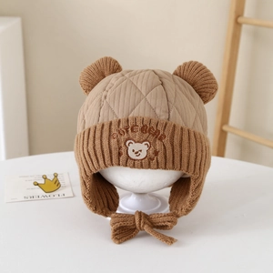 Detail of baby winter hat featuring bear ears and cute bear embroidery on quilted fabric