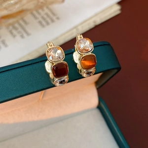 Macro shot of vintage gold earrings with amber and clear square gems on a jewelry box