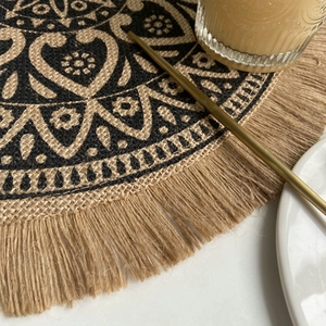 Round woven jute placemat with black mandala print and fringe tassels for home decor