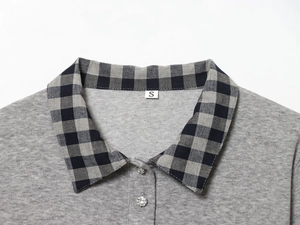 Detail of grey polo shirt collar with black plaid trim and rhinestone decorative buttons