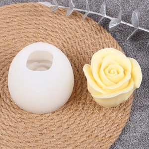 Detail view of yellow rose candle and round silicone mold on a textured woven mat