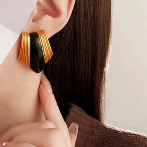 Close-up of vintage gold French style earrings with black enamel inlay on female model