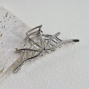 Detailed view of silver spider web hair claw clip with hollow metal design for Halloween